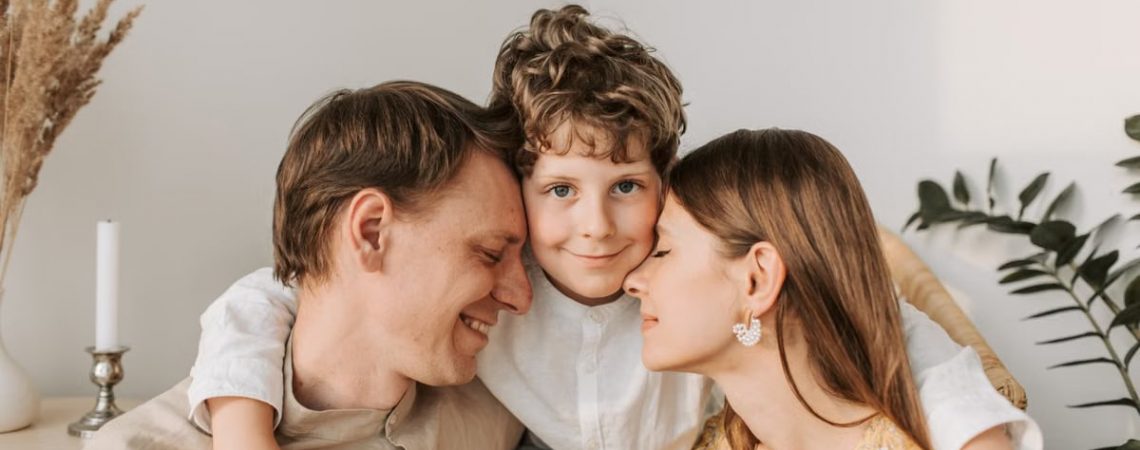 A joyful family moment with parents and their son embracing indoors.